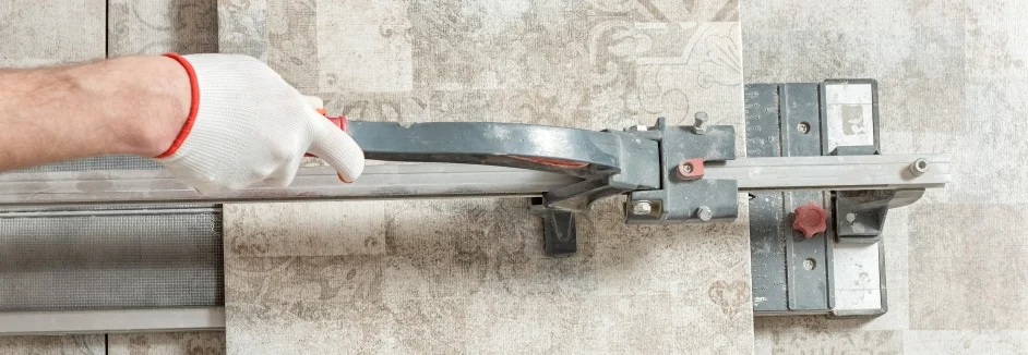 Hand schneidet Fliese mit Schneider